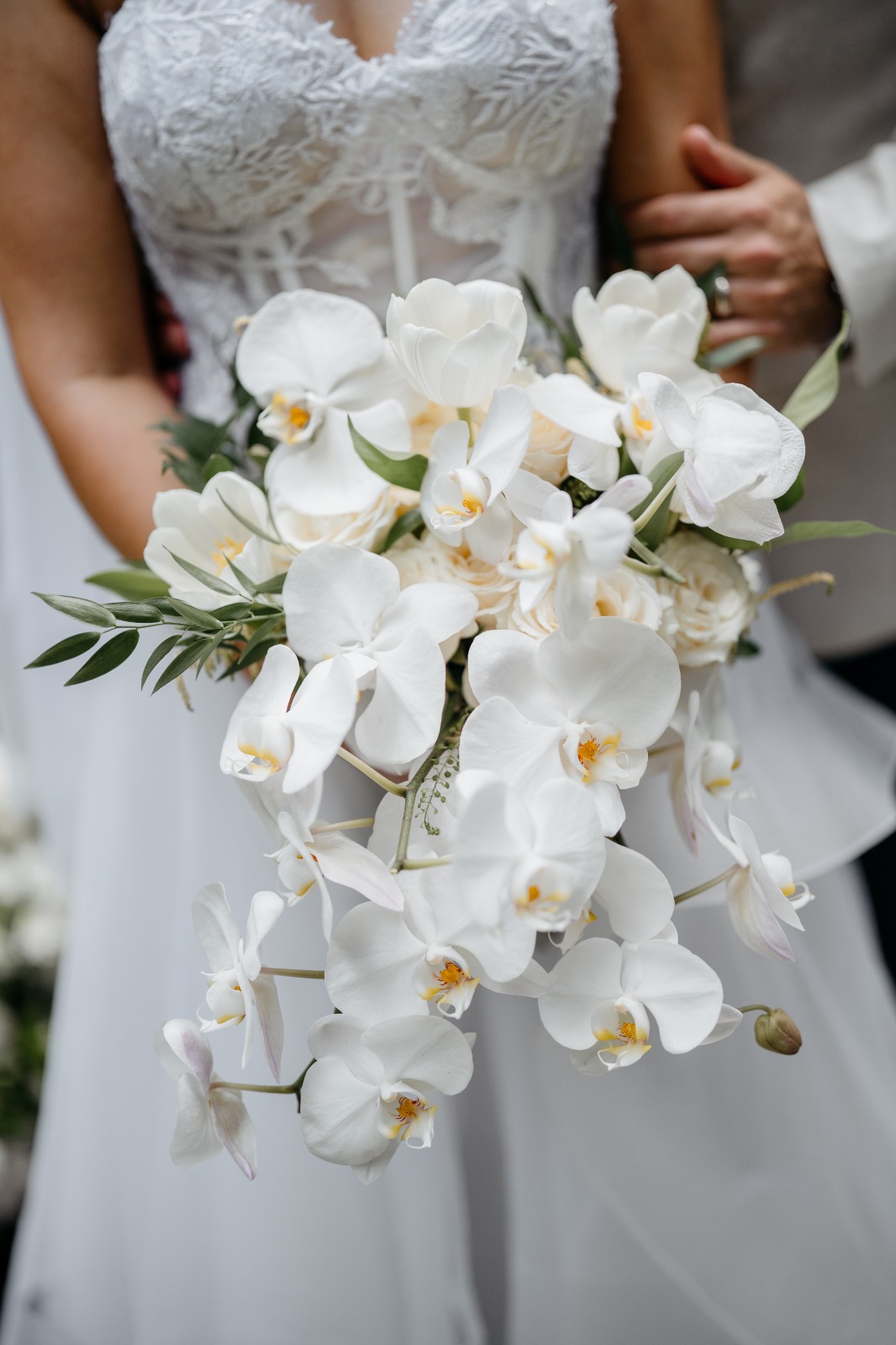 Bride kissing her groom while holding a white bridal bouquet by Lammar Flower Studio Bali
