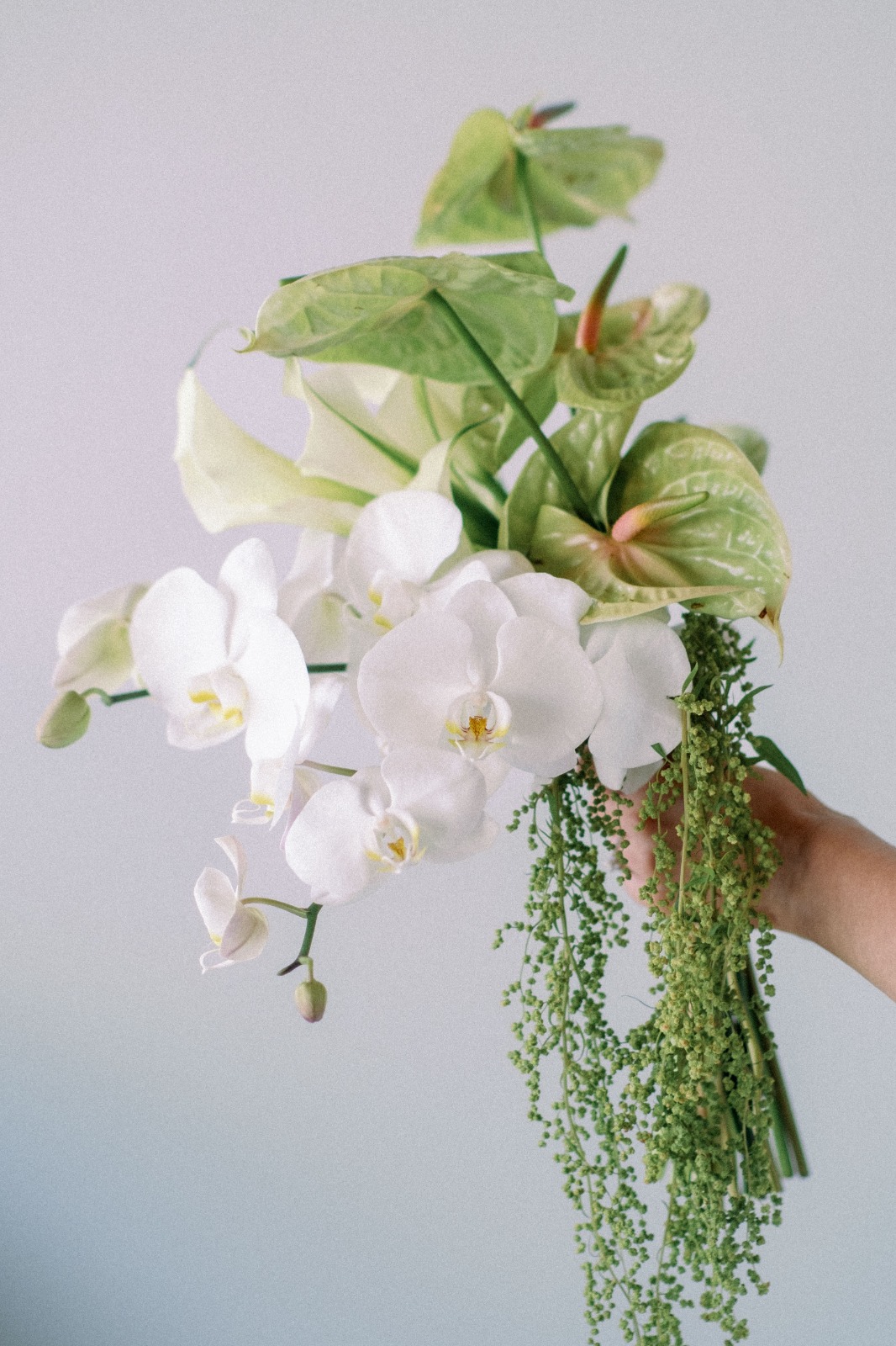 Bride kissing her groom while holding a white bridal bouquet by Lammar Flower Studio Bali